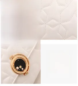 Détail de la texture en cuir blanc matelassé en étoile et serrure ronde dorée avec perles