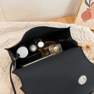 Petit sac bandoulière noir imprimé or montrant le grand espace interne pour mobile et maquillage