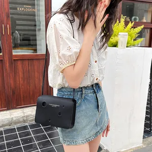 Sac à bandoulière en cuir noir avec découpes circulaires et marquage doré élégant