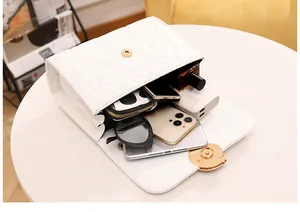Vue détaillée de l'intérieur spacieux d'un sac bandoulière blanc brodé avec objets divers