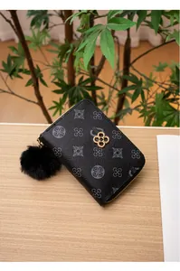 Dettaglio del portafoglio a fiori con chiusura a quadrifoglio dorata e pompon nero