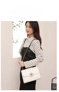 Détail du sac à bandoulière blanc avec matelassage cœur, chaîne dorée et boucle strass