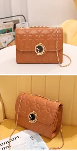 Détail de surpiqûres en étoile et fermoir doré rond sur sac bandoulière en cuir