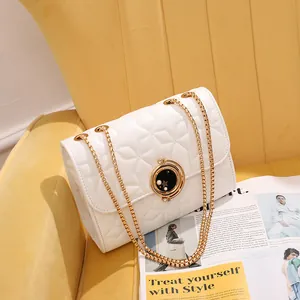 Sac bandoulière blanc matelassé avec serrure étoile et chaîne dorée sur siège jaune