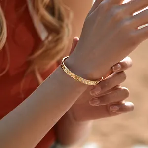 Detailed view of 18K gold-plated brass chain bracelet on a woman wrist in soft lighting