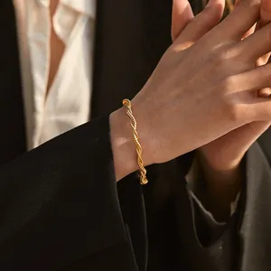 Detailed view of an 18K gold plated brass twisted rope bracelet on a woman's wrist