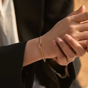 Detail of elegant 18K gold-plated brass bangle with circular geometric charm on wrist