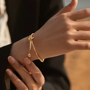 Polished 18K gold-plated brass knot bracelet with rounded ends worn on a model's wrist