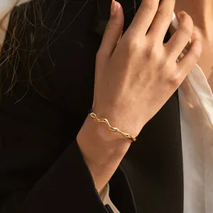 Close-up of 18K gold plated wavy bangle on model with business casual suit background