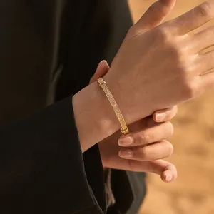 Close-up of a 18K gold plated multi-strand mesh bracelet worn with a dark blazer cuff