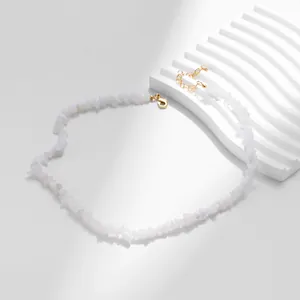 Detail van witte stenen ketting met verstelbare gouden sluiting op gipsen ondergrond
