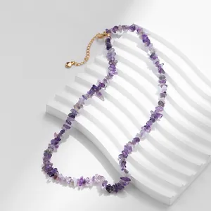 Macro-opname van de boho-ketting met paarse kristallen en gouden karabijnsluiting