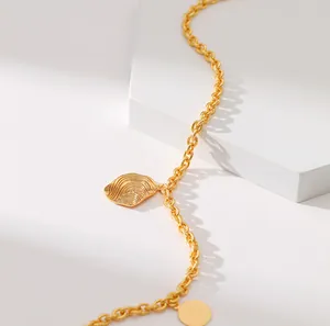 Detailaufnahme der goldenen Metallkette mit Wellenanhänger und runder Metallplakette