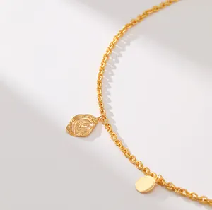 Nahaufnahme der goldenen O-Kette mit wellenförmigem Anhänger und glatter runder Scheibe
