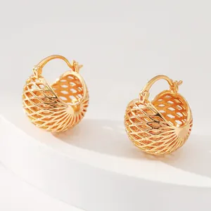Macro detail of gold-plated hollow sphere earrings with intricate woven mesh texture