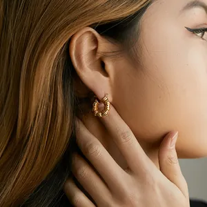 Nahaufnahme eines Modells mit goldenem Messingohrring mit einzigartiger Faltenstruktur
