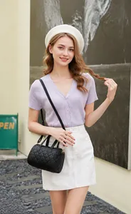 Lifestyle view of women's quilted cylinder bag with purple cardigan and white skirt