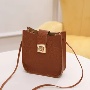 Mini sac bandoulière marron motif litchi avec fermoir doré sur table blanche