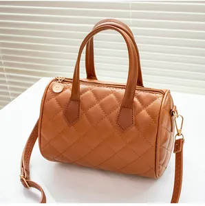 Detail view of brown quilted cylindrical bag with golden hardware and long shoulder strap