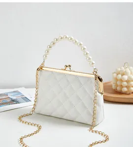 Detail van witte gewatteerde crossbodytas met parelhandvat en gouden metalen sluiting