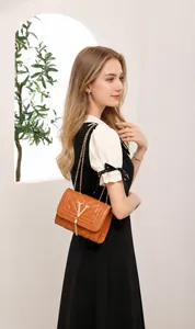 Detailed view of brown crossbody bag featuring V-shaped quilting and gold metal logo