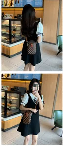 Brown checkered mobile phone crossbody bag with metal chain shown on a model in a cafe