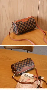 Nahaufnahme des braunen Karomusters und des Leder-Markenpatches auf der Zylindertasche