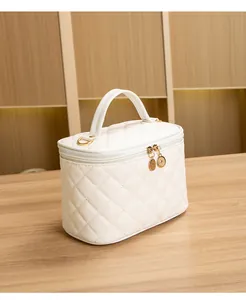 Détail d'une trousse de maquillage matelassée blanc crème avec doubles fermetures éclair dorées