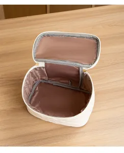 Vue de dessus d'une trousse à maquillage blanche matelassée avec doublure marron et zip doré