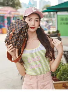Sac bandoulière marron à damier avec boucle en métal et large sangle porté par mannequin
