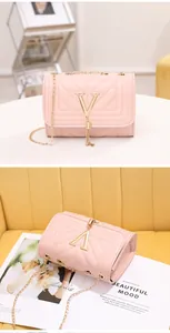 Detailed view of pink V-quilted small square bag with golden chain and tassel accent