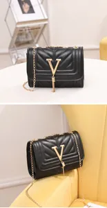 Detailed view of black V-quilted faux leather bag with gold hardware and tassel detail