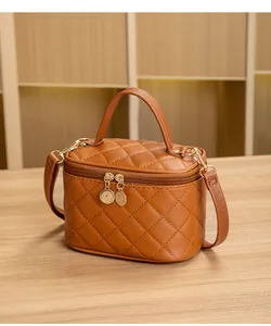 Détail d'un sac marron matelassé avec double fermeture éclair dorée et poignée en cuir