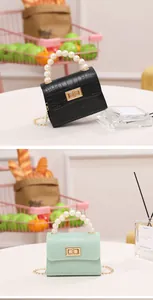 Detalle de mini bolso con grabado de cocodrilo, asa de perlas y cierres metálicos