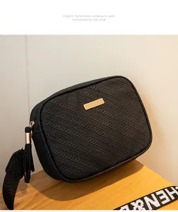 Detail of black crossbody bag with woven texture, golden hardware and tassel zipper