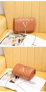 Detail of V-quilted brown leather crossbody bag with golden chain strap and tassel