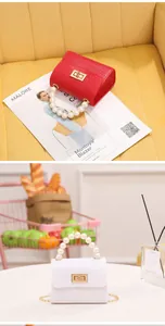 Detalle de mini bolsos rojos y blancos con asa de perlas y textura de cocodrilo