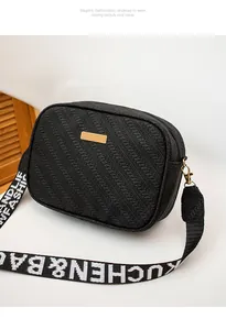 Close-up of black woven texture crossbody bag with gold plate and branded strap
