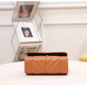 Detail of warm brown chevron quilted leather flap bag with golden metal clasp