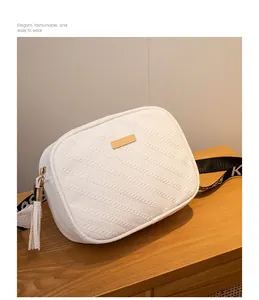 Detail of white textured mini crossbody bag with gold metal plate and tassel zipper