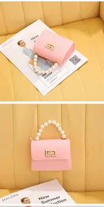 Mini bolso rosa con grabado de cocodrilo, asa de perlas blancas y cierre de giro dorado