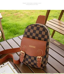 Détail d'un sac de poitrine marron à carreaux avec boucles dorées et logo métal