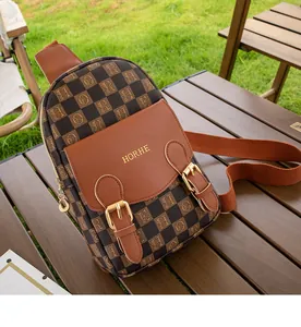 Gros plan sur un sac de poitrine à carreaux marron avec logo doré sur table en bois