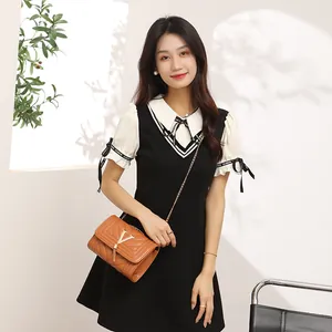 Women's black and white V-neck dress paired with brown quilted chain crossbody bag