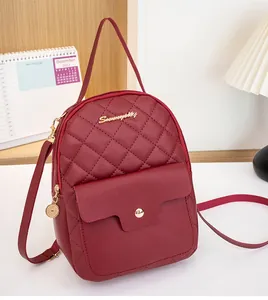Close-up of wine red quilted mini backpack with gold logo and functional metal buckle