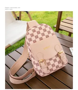 Détail du sac de poitrine rose et beige à carreaux avec boucle dorée sur table en bois