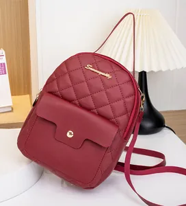 Detail shot of wine red quilted PU leather mini backpack with gold logo and front pocket