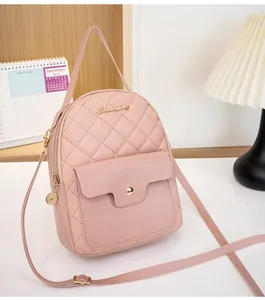 Close-up of pink quilted mini backpack featuring gold zippers and front flap pocket detail
