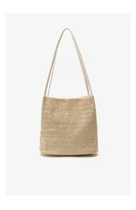 Detail of woven straw texture and cream leather straps on the summer bucket bag