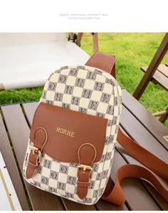 Détail du sac à bandoulière à carreaux avec logo doré gravé sur le rabat en cuir
